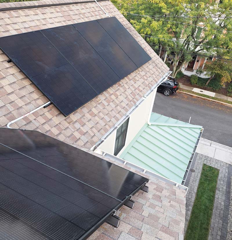 High-efficiency black solar panels installed on a multi-level residential roof by Cosmo Solaris, featuring a 30-year power production guarantee and seamless integration.