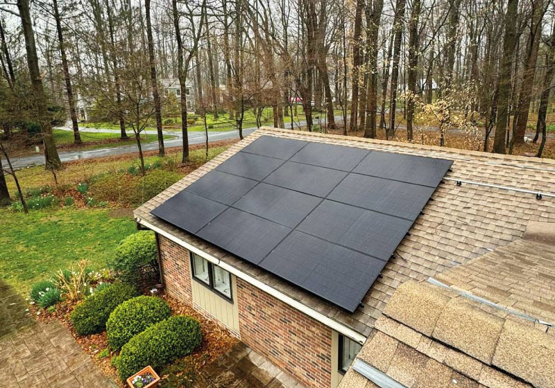 Large-scale solar panel grid installed by Cosmo Solaris on a brick residential outbuilding, featuring a transferable warranty that adds long-term value to the property.